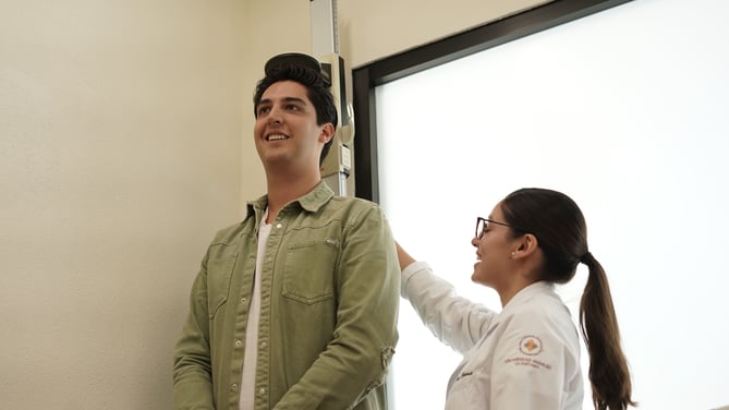 Estudiante de nutrición mide la estatura de su paciente.