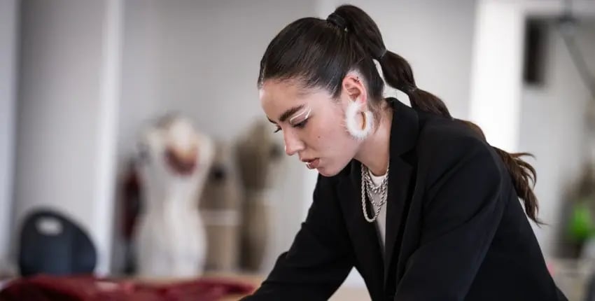 Estudiante de la Licenciatura de diseño de moda de la Anáhuac querétaro realizando unos cortes a textiles