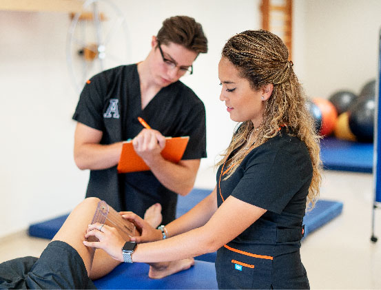 Estudiantes de la licenciatura en Terapia Física haciendo una revisión en la rodilla a un paciente.