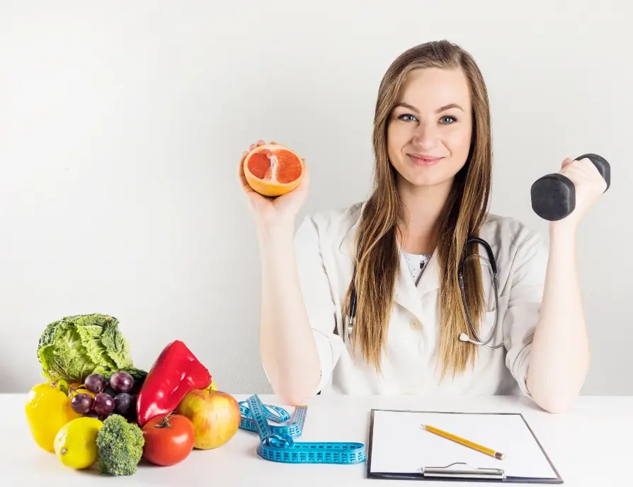 Una mujer con bata realizando actividades que hace un nutriólogo, escribiendo en un formulario con frutas y verduras en su escritorio