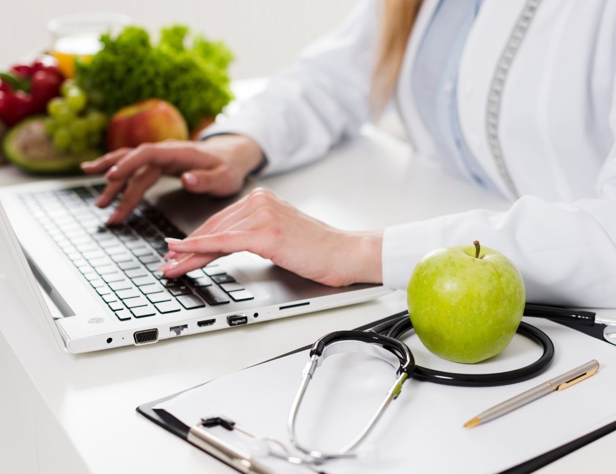 Licenciada en Nutrición haciendo dieta con manzana verde y documento