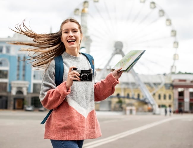mujer joven con una cámara en la mano enfrente del London Eye