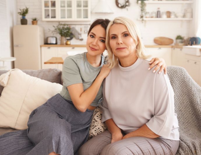 Madre e hija sentadas charlando en el sofa celebrando el dia de las madres